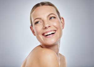 Mujer recibiendo tratamiento facial iluminador profesional en clínica estética preparándose para eventos navideños con piel radiante luminosa